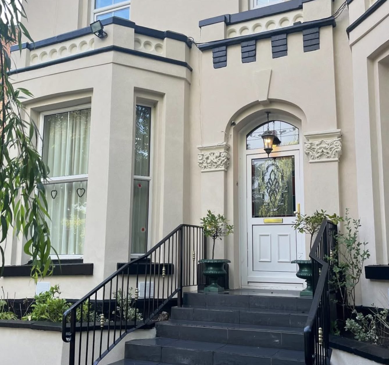 Victorian bay front in cream render with an ornate door surround and steps